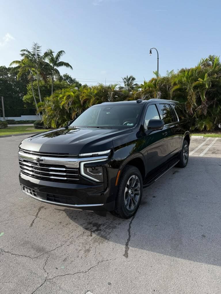 Black Chevrolet Suburban for private car service in Miami, parked beside palm trees